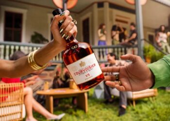 A Courvoisier VS bottle being passed between two hands at a house party, from the Pass The Courvoisier campaign