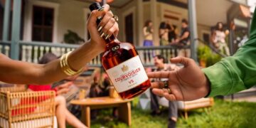 A Courvoisier VS bottle being passed between two hands at a house party, from the Pass The Courvoisier campaign